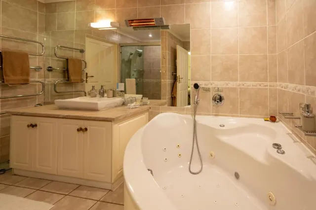 En-suite bathroom with corner spa bath and heated towel rail