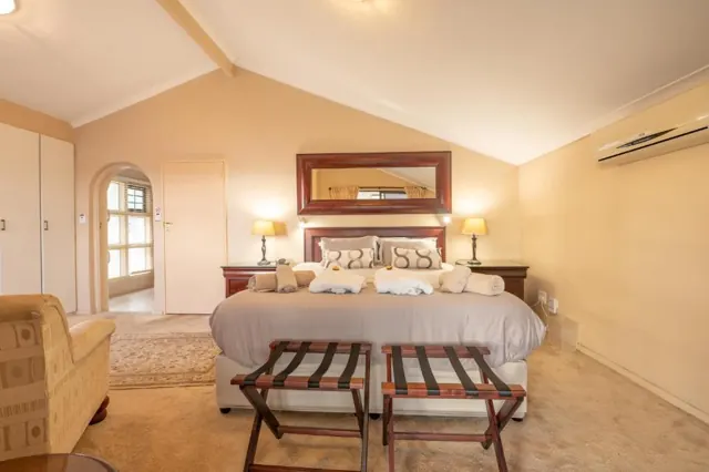 King bedroom under a vaulted ceiling with luggage racks at the foot of the bed