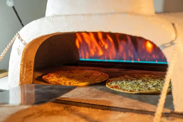Two pizzas baking in the gas-fired pizza oven